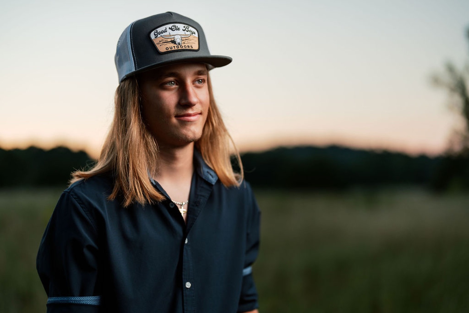 Senior in a trucker cap at dusk in an open field