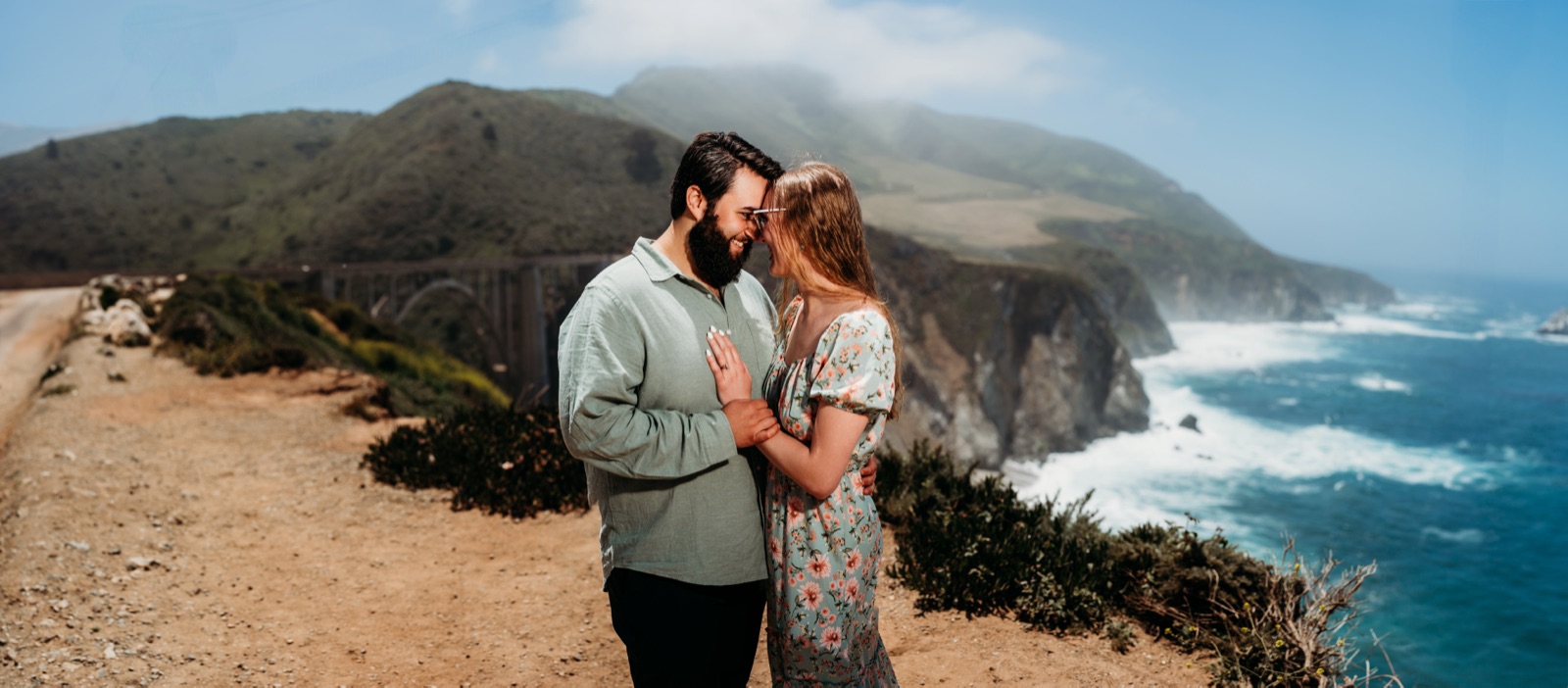 Couple standing together on a cliff above the Big Sur coastline