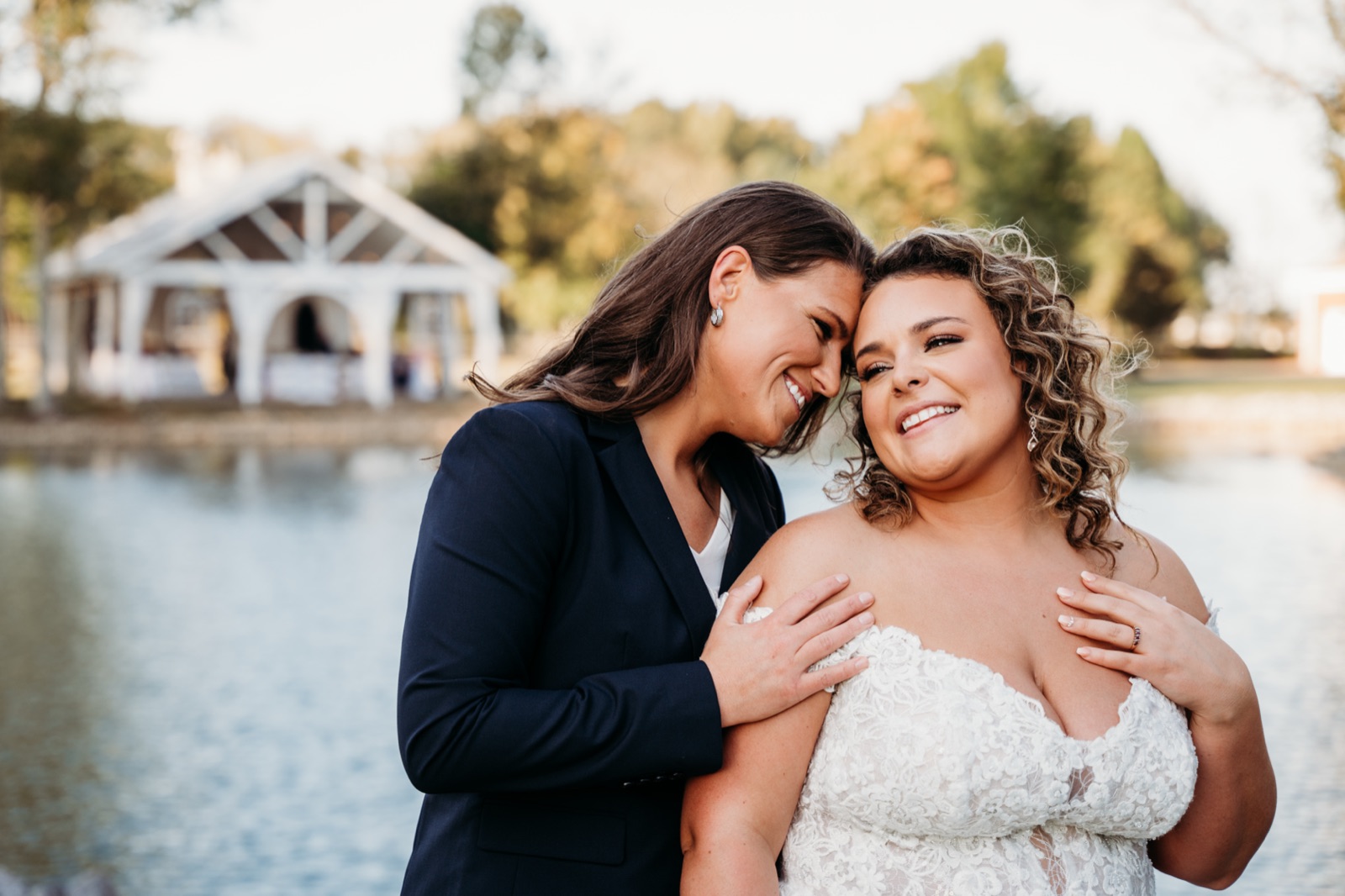 Two brides laughing together by the water
